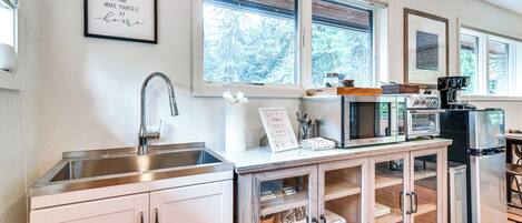 Una cocina moderna con un lavamanos de acero inoxidable, una cafetera y un refrigerador.