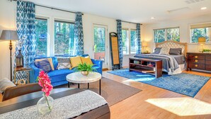 Un salon moderne avec un canapé bleu, un lit en bois et de grandes fenêtres.