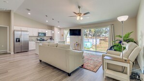 A spacious living room with a large sofa, a coffee table, and a ceiling fan. - 2 Mi to Rainbow Springs: Home w/ Hot Tub! (Dunnellon)