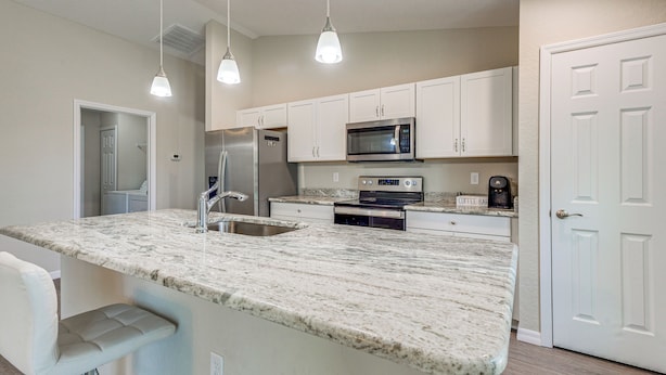 A modern kitchen with white cabinets, a stainless steel refrigerator, a microwave, and a coffee maker on the countertop. - 2 Mi to Rainbow Springs: Home w/ Hot Tub! (Dunnellon)