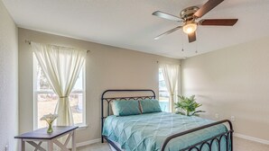 A bedroom with a bed, a nightstand, a ceiling fan, and a window with curtains. - 2 Mi to Rainbow Springs: Home w/ Hot Tub! (Dunnellon)