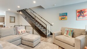 Ein modernes Wohnzimmer mit einem Ecksofa, einem kleinen Sofa und einer Treppe mit Metallgeländer.