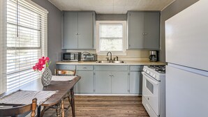 A kitchen with grey cabinets, a wooden dining table, a microwave, a toaster, a sink, and a stove. - Near Sabine Lake & Refineries: Pet-friendly Apt (Port Arthur)
