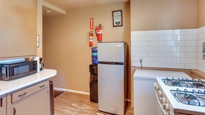 La cuisine est équipée d’un four à micro-ondes, d’un réfrigérateur et d’une cuisinière. Un distributeur d’eau et un extincteur sont fixés au mur.