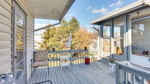 Une terrasse en bois avec un espace abrité, une chaise, une petite table et un seau rouge.