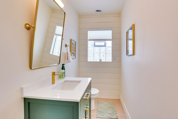 A bathroom with a white sink, a green cabinet, a toilet, and a window with blinds. - 3 Mi to Dtwn & Ysu: Updated Youngstown Home (Youngstown)
