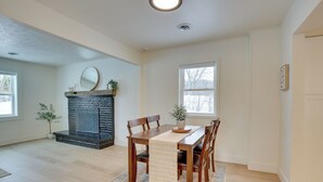 Un comedor con una mesa de madera, sillas, una chimenea y una alfombra.