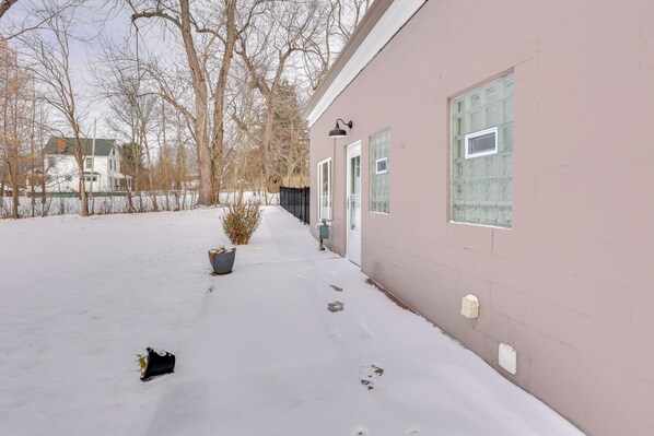 A snow-covered pathway leading to a building with a pink exterior and multiple windows.