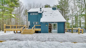 Ein blaues Gebäude mit verschneitem Dach und einer Holzterrasse.