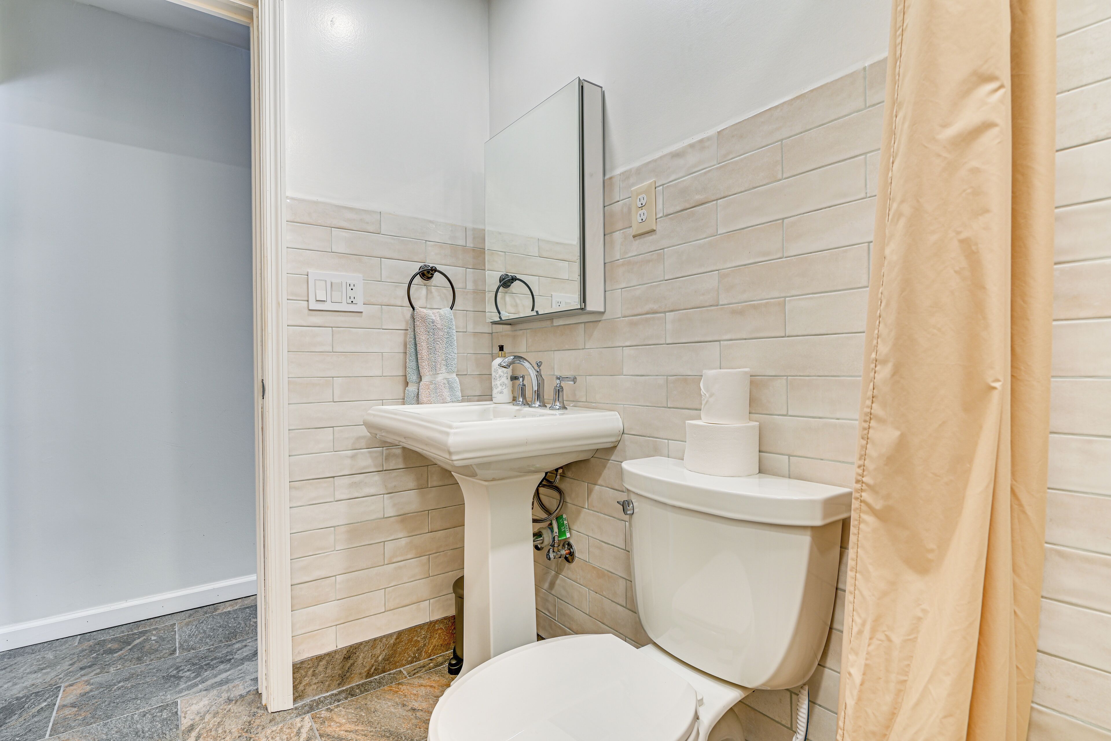 Baño con lavamanos, espejo y retrete blancos.
