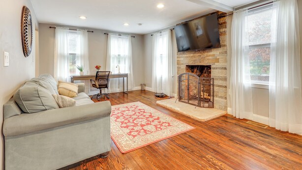 Una sala de estar con sofá, chimenea, televisor montado en la pared y una zona de comedor con mesa y sillas.