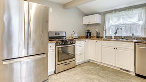 Una cocina moderna con electrodomésticos de acero inoxidable, armarios blancos y encimera de granito.