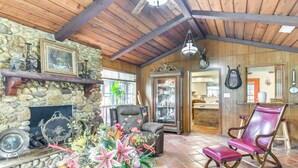 A rustic interior with a stone fireplace, leather armchairs, and a variety of decorative items. - Family Home on 30 Acres in Manvel! (Manvel)