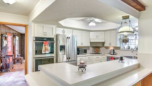 A modern kitchen with white cabinetry, stainless steel appliances, and a large island. - Family Home on 30 Acres in Manvel! (Manvel)