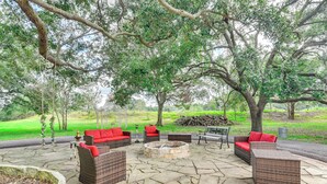 An outdoor patio area with wicker furniture and a stone fire pit. - Family Home on 30 Acres in Manvel! (Manvel)