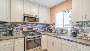 Una cocina moderna con armarios blancos, electrodomésticos de acero inoxidable y un salpicadero de azulejos.