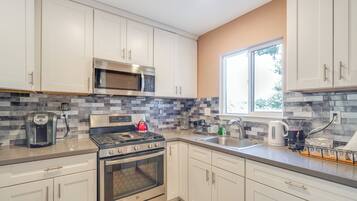 A modern kitchen with white cabinets, stainless steel appliances, and a tiled backsplash.