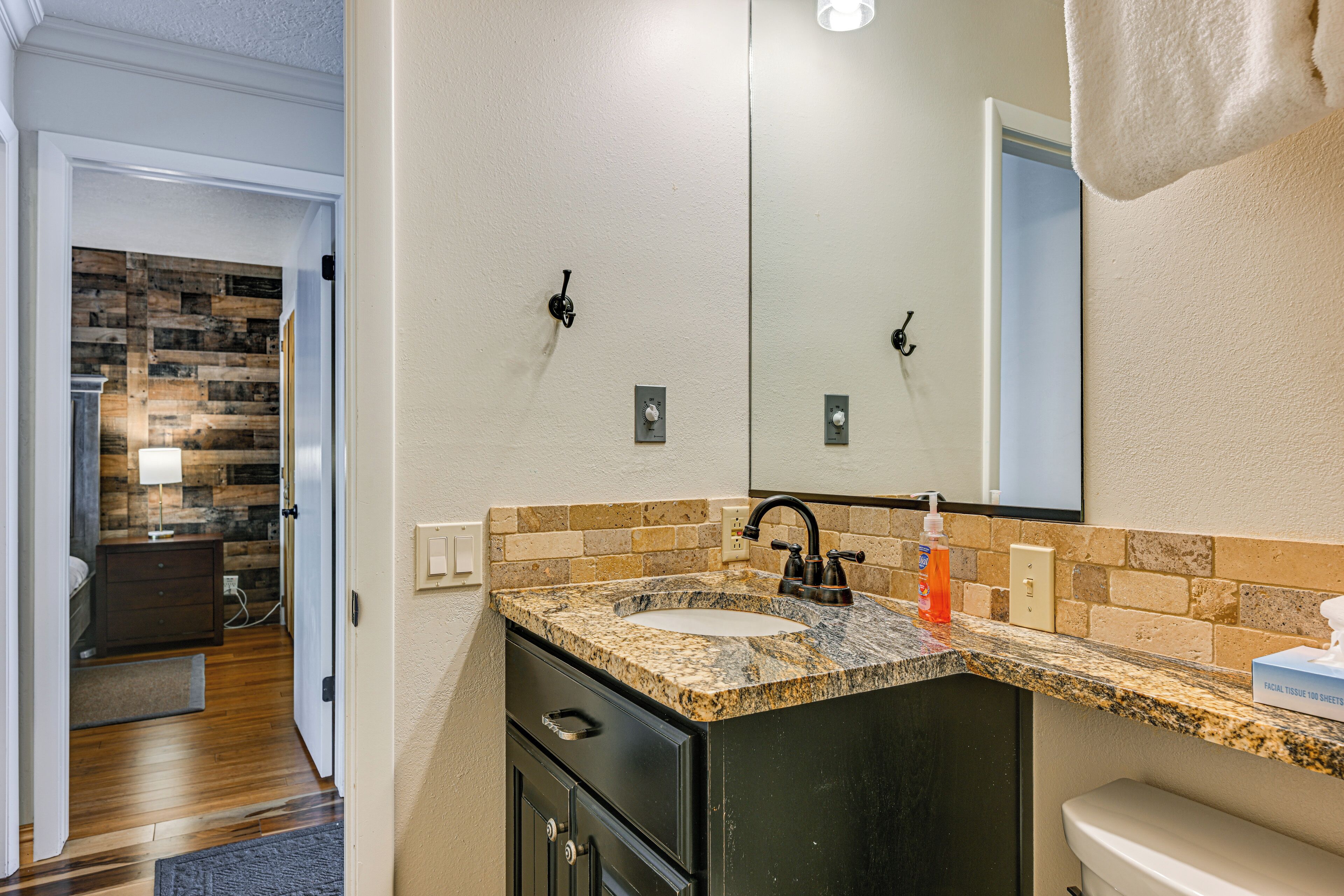 Une salle de bain avec un comptoir en granit, un lavabo noir et un miroir.