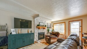 Ein Wohnzimmer mit einem großen Ledersofa, einem türkisblauen Schrank, einem Flachbildfernseher, einem Kamin und einer Wand mit Steinverkleidung.