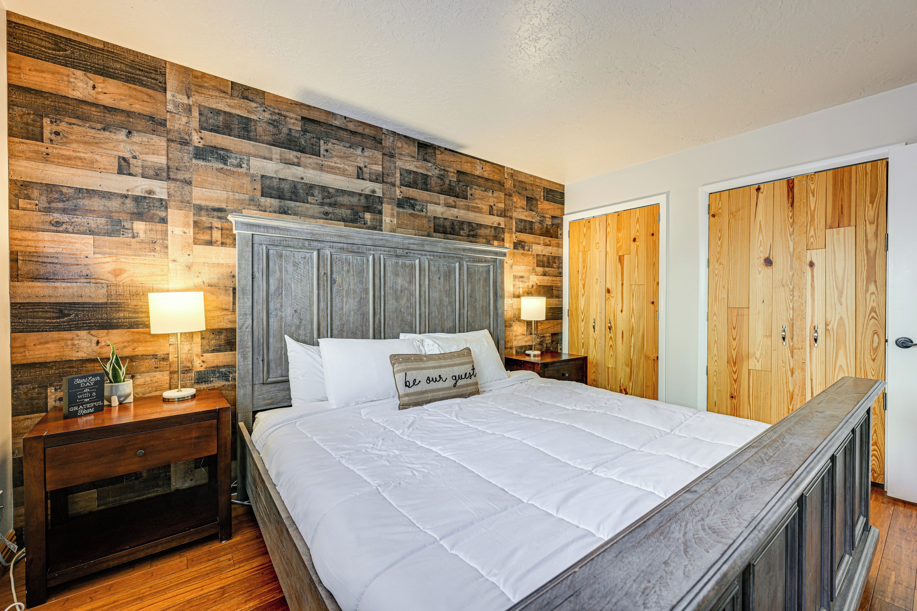 A bedroom with a wooden headboard, a bed with white bedding, two bedside tables with lamps, and a wooden wardrobe.