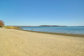 A sandy beach with clear blue water and a distant island. - Walk to Grays Beach Park: Kingston Seaside Escape (Kingston)