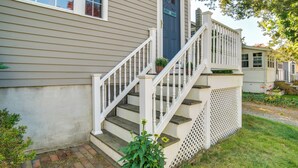 A house with a front porch, a staircase with white railings, and a small garden area. - Walk to Grays Beach Park: Kingston Seaside Escape (Kingston)