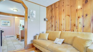A living room with a beige sofa, wooden paneling on the wall, a small table, and a colorful rug. - Walk to Grays Beach Park: Kingston Seaside Escape (Kingston)