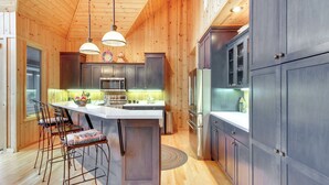 Une cuisine moderne avec des murs en bois, des appareils en acier inoxydable et un îlot central doté de tabourets de bar.