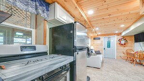 Una cocina compacta con estufa, refrigerador y un comedor con mesa y sillas.