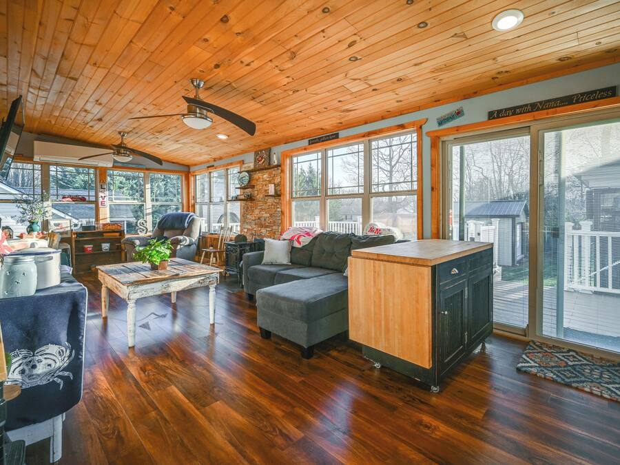 A spacious living room with a wooden ceiling, large windows, a fireplace, and a cozy seating area.
