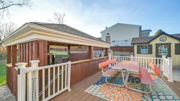 A wooden deck with a picnic table and benches, surrounded by a white fence.