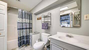 A bathroom with a toilet, sink, and shower curtain.