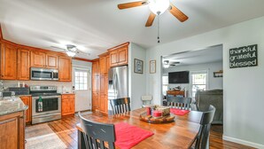 Una cocina moderna con armarios de madera, electrodomésticos de acero inoxidable y una zona de comedor con mesa y sillas de madera.