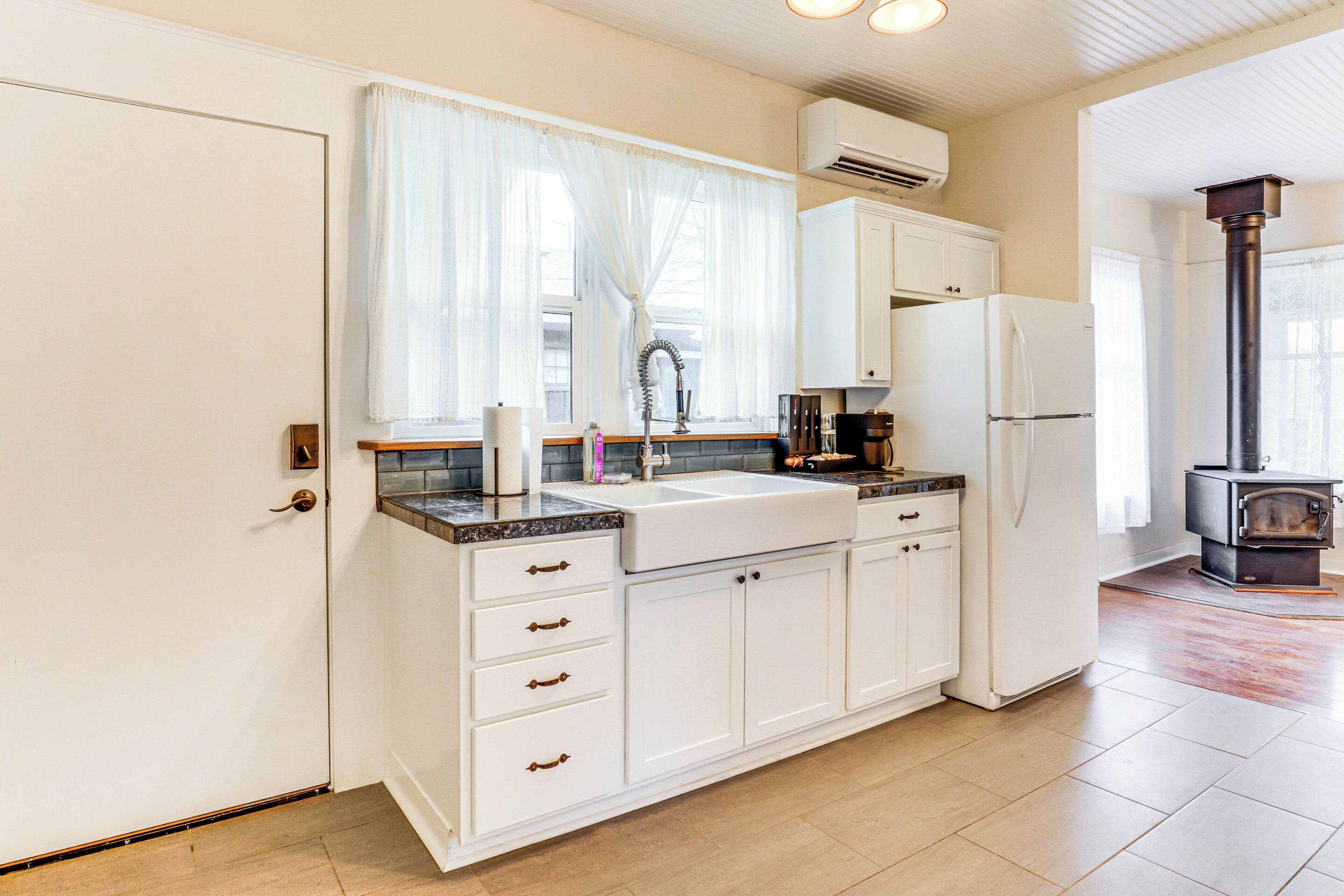 A kitchen with white cabinets, a double sink, a stove, and a refrigerator.