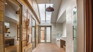 A modern bathroom with a skylight, wooden accents, and a large mirror. - The Pigs (Melton Constable)
