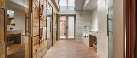 Un baño moderno con tragaluz, detalles de madera y un espejo grande.