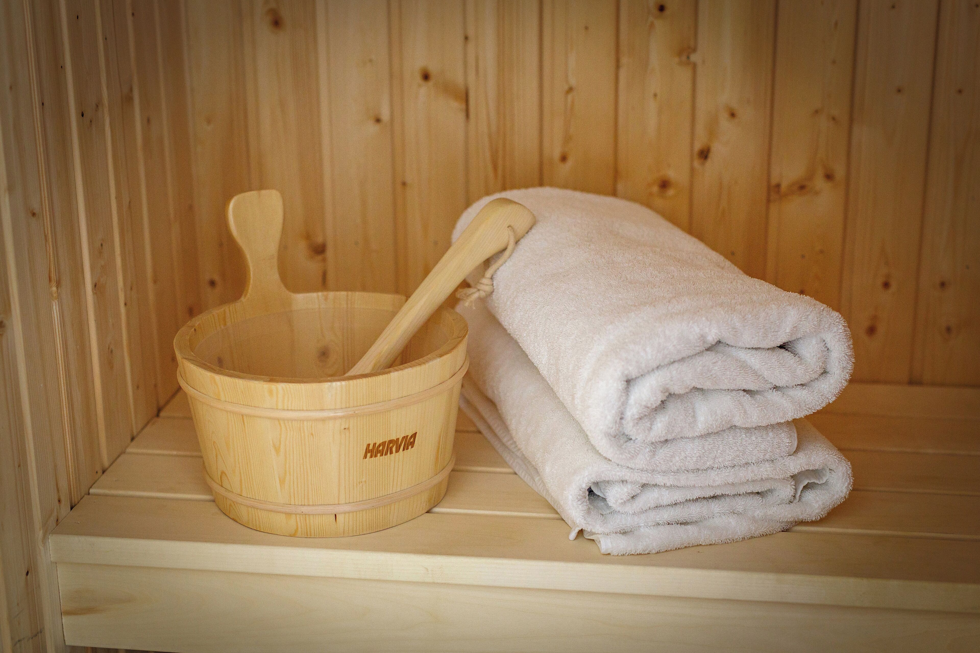 A wooden sauna with a wooden basin and a folded towel.