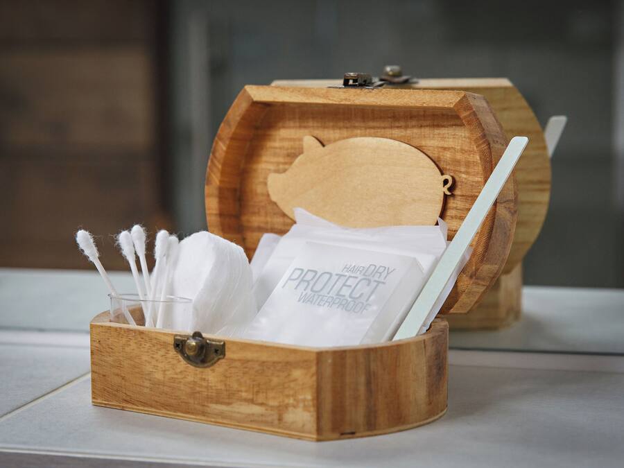 A wooden box with a lock, containing a toothbrush, a white cloth, and a bag labeled "HAIR DRY PROTECT WATERPROOF."