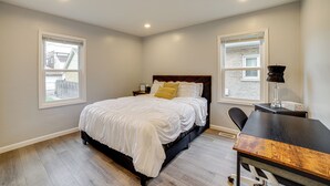Un dormitorio con una cama, un escritorio y dos ventanas.
