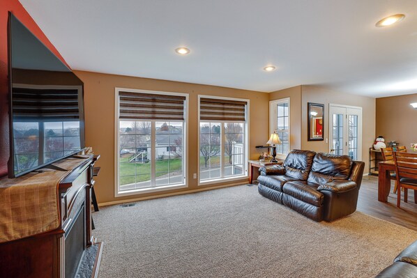 A living room with a fireplace, a leather couch, and a dining area with a table and chairs. - 6 Mi to Dtwn Lewiston: Quiet Home w/ Views (Clarkston)