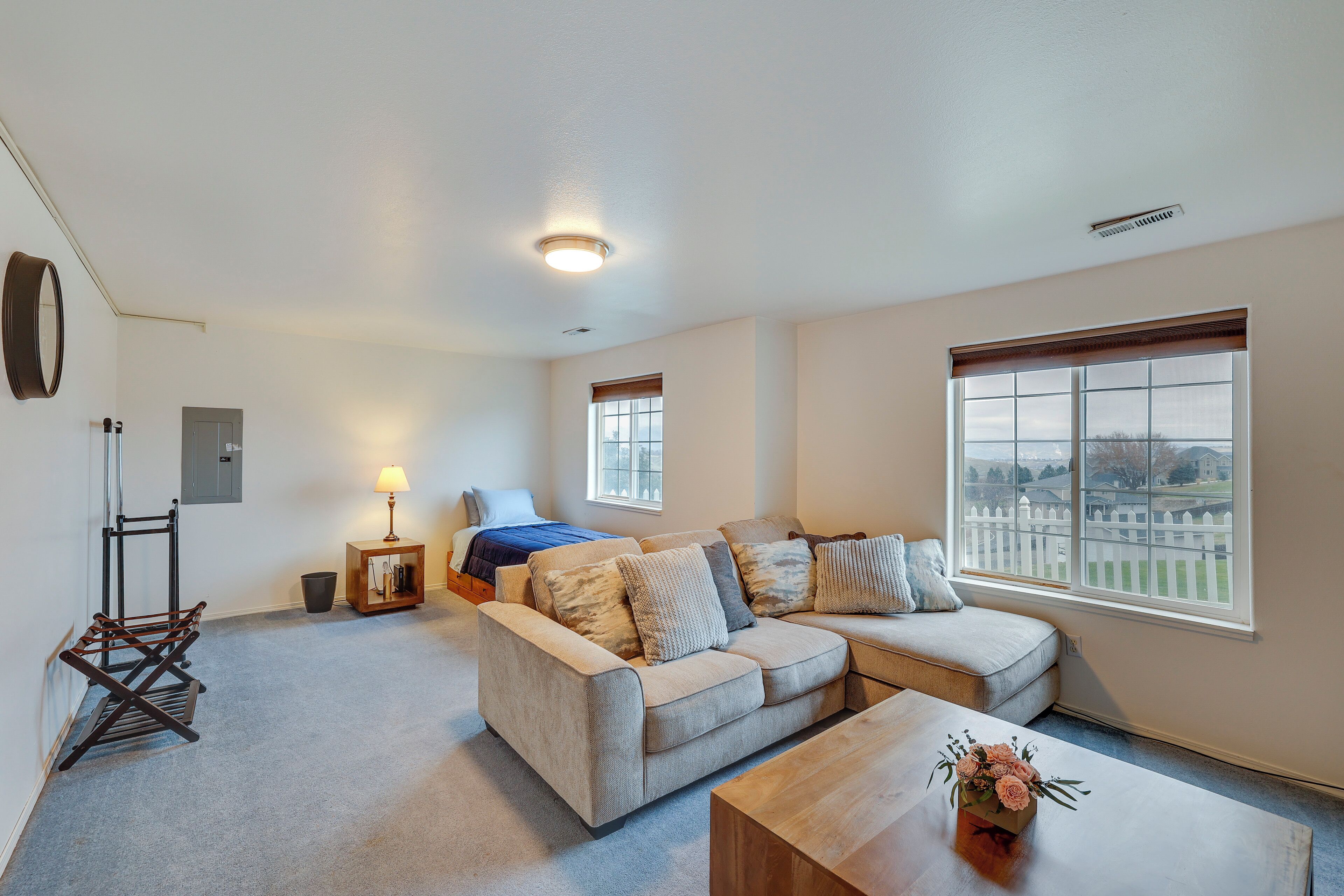 A spacious living room with a large window, a sofa, a coffee table, and a lamp.