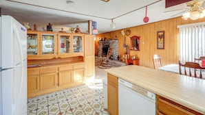 Una cucina con mobili in legno, lavastoviglie e pavimento piastrellato.