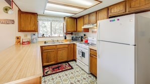 Una cucina con mobili in legno, un frigorifero bianco, un forno a microonde e un fornello.