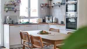 A modern kitchen with white cabinets, a dining table with chairs, and a window providing natural light. - Superb House in the Gare District - Angers, for 4 People (Angers)