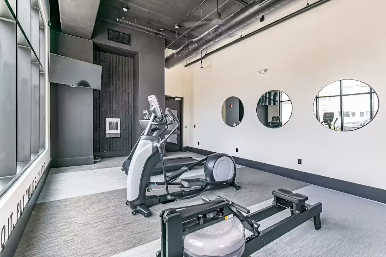 A gym with treadmills, elliptical machines, and a weight bench.