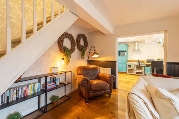 A living room with a staircase, a fireplace, and a kitchen in the background.