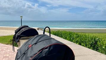 Un camino pavimentado con bolsas negras sobre bancos con vista a una playa.