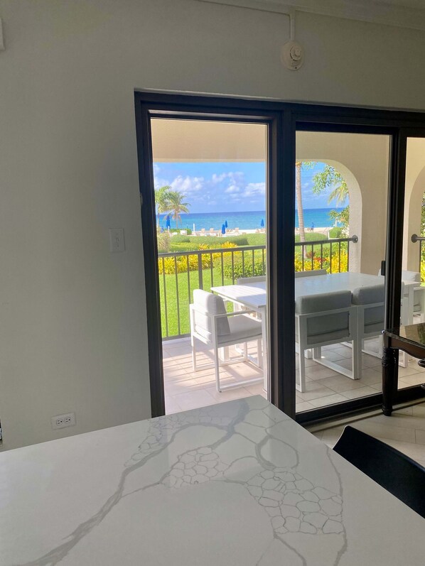 A room with a view of a balcony, a dining table, and a white sofa.