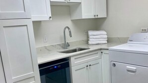 Cocina moderna con armarios blancos, lavavajillas integrado, un fregadero y una lavadora Whirlpool.