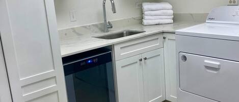 Une cuisine moderne avec des meubles blancs, un lave-vaisselle encastré, un évier et un lave-linge Whirlpool.